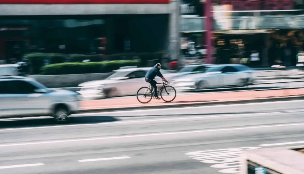 Radfahrer auf einem Fahrradweg neben einer befahrenen Straße mit Autos